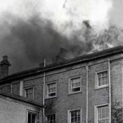 Flames and smoke can be seen rising from the roof of Hindlip Hall as police officers dash to rescue documents
