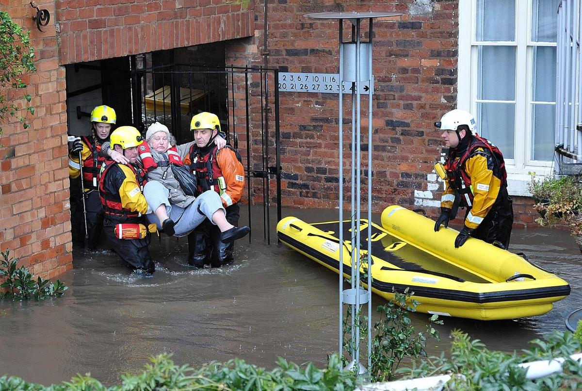 A resident of John Gwynn House, Worcester, is carried through the flood water by members of the Hereford and Worcester Fire and Rescue Service. 0714520412