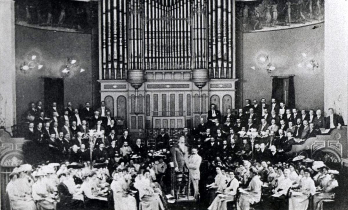 Vanished Worcester. Sir Edward Elgar (light suit) stands next to Sir Ivor Atkins who is on the conductor’s podium at a rehearsal in the Public Hall, Worcester, for a Worcester Three Choirs Festival performance of the Dream of Gerontius in 1905