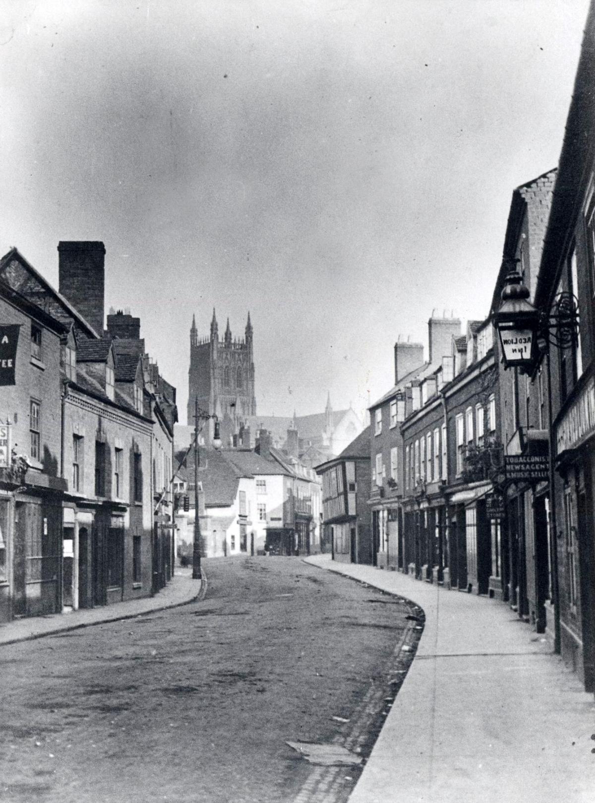 The familiar curve of Sidbury, about 100 years ago, with the cathedral tower in the background and shops lining its south side. The row on the right, including the entrance to the Commandery, survive today.