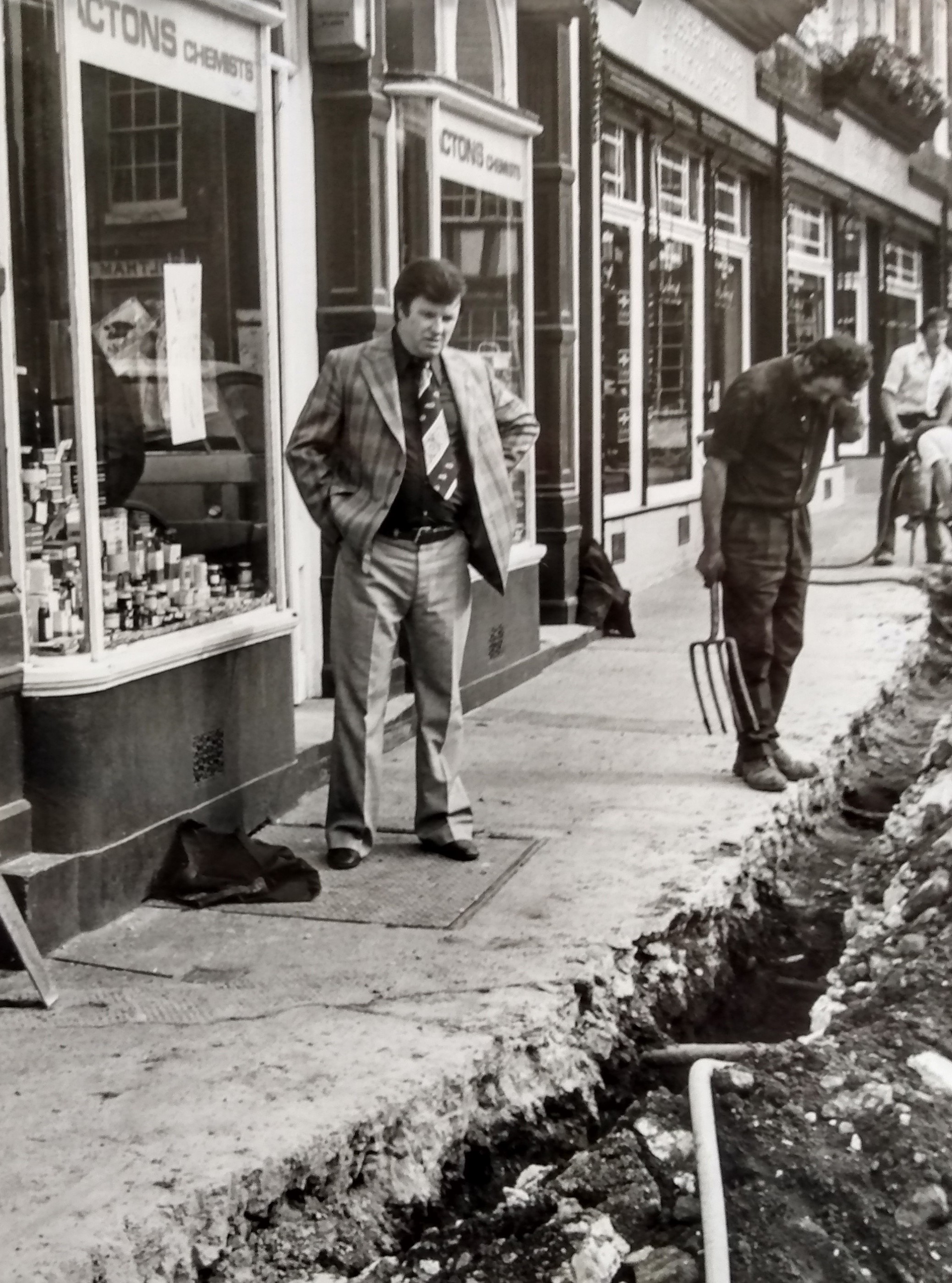 September 1976 and Peter Lewis, owner of Acton’s Chemist looks on in dismay at the work going on outside his shop