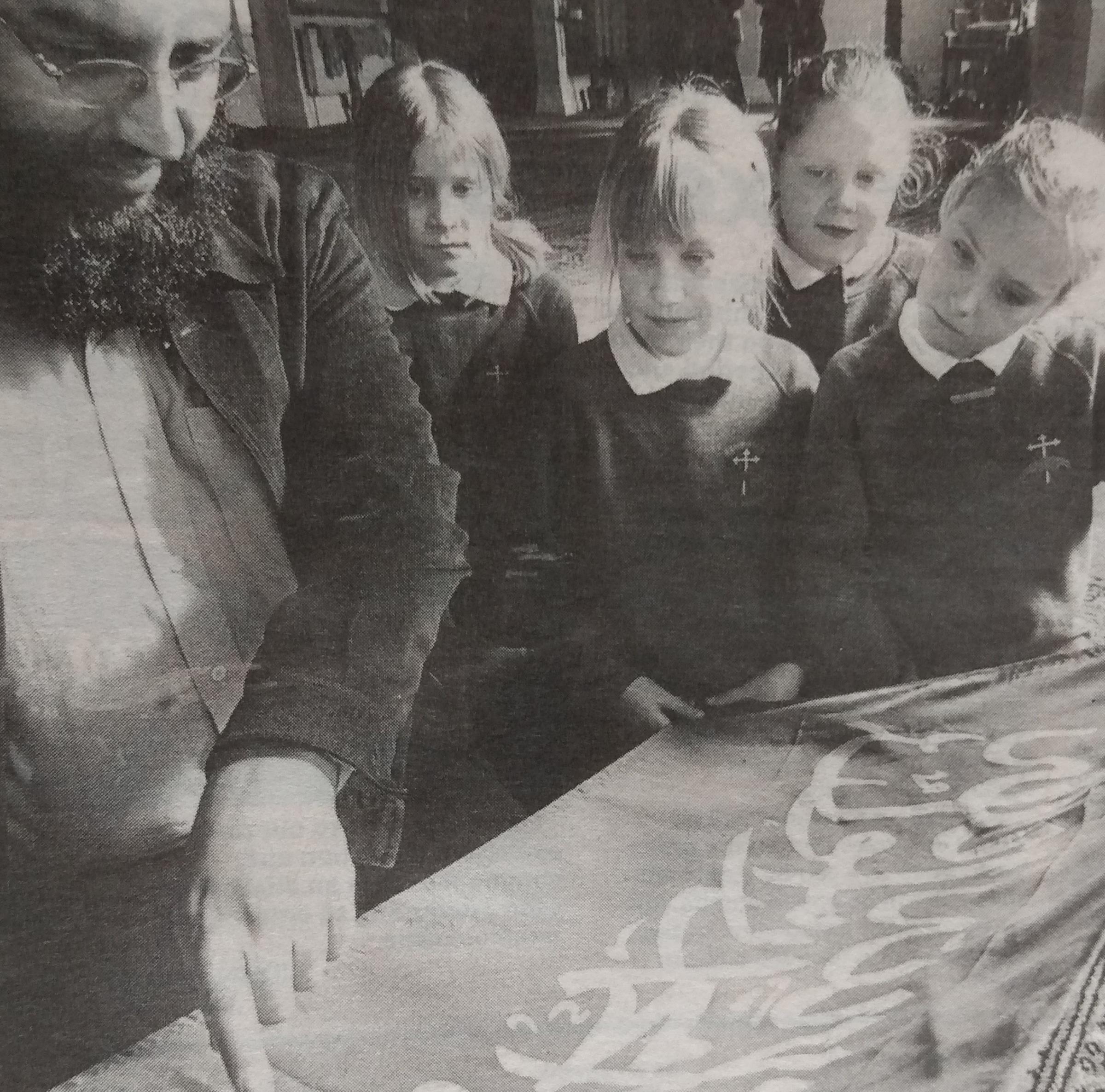 Sajid Riasat, from Worcester Muslim Welfare Association, showing Eckington CE First School pupils a flag decorated with Arabic script of the first pillar of Islam during a school visit to the city mosque in March 2005