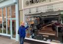 CONCERN: John Cooke outside Cranes Music, pointing to his guitar. The shop sells music products by Yamaha, Korg, Casio, Roland,