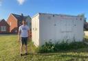 Shaun Barnes stood next to a shed that has been in place at the site for over a year on the communal grass.