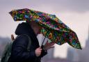 STORM: Woman struggles to keep umbrella open