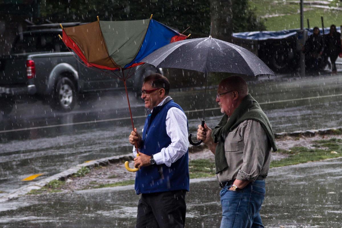 Men walk in the rain with umbrellas