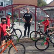 Pupils beside their new bike shed as top 4X pro rider Scott Beaumont cuts the ribbon to officially open it