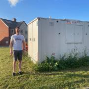 Shaun Barnes stood next to a shed that has been in place at the site for over a year on the communal grass.