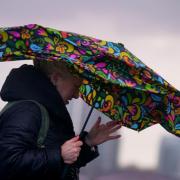 STORM: Woman struggles to keep umbrella open