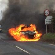 TERRIFYING: Jodie Buckley's Suzuki Swift caught fire in Powick - the van of the driver who helped her out is parked behind the burning car