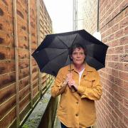CONCERNS: Julie Clayton, warden at Nash's and Wyatt's Almshouses, illustrates with an umbrella how close the bar beer garden is to people's homes